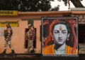 Security personnel walk past a poster of Lord Ram, ahead of the consecration ceremony of Ram Mandir, in Ayodhya, on January 20.(PTI)
