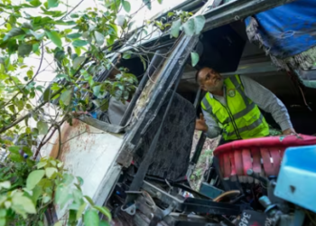 A forensic official inspects a bus that fell into a deep gorge on Sunday after being fired at by terrorists in Reasi district, Jammu and Kashmir, Monday, June 10, 2024.(AP)