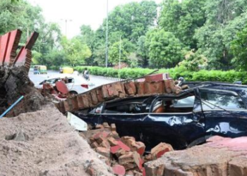 A damaged car under the debris of a boundary wall in Daryaganj. (PTI)