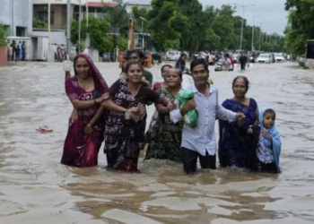 A family wades through a flooded road following heavy rainfall in Ahmedabad, Gujarat. (AP Photo)(HTPRINT)
