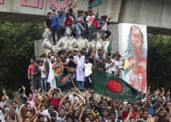 Protesters climb a public monument as they celebrate the news of Prime Minister Sheikh Hasina's resignation, in Dhaka, Bangladesh, on Monday. (AP)