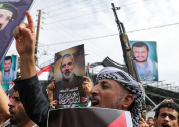 Protesters hold posters of Hezbollah senior commander Fuad Shukr and assassinated Hamas chief Ismail Haniyeh