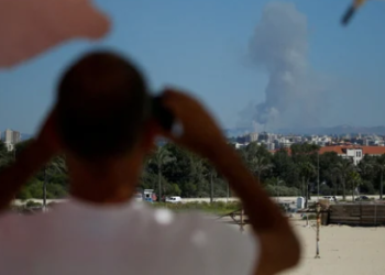 A man watches as smoke billows over southern Lebanon following an Israeli strike, amid ongoing cross-border hostilities between Hezbollah and Israeli forces.(REUTERS)