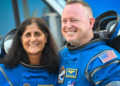 NASA astronauts Butch Wilmore (R) and Suni Williams, wearing Boeing spacesuits, depart the Neil A. Armstrong Operations and Checkout Building at Kennedy Space Center for Launch Complex 41